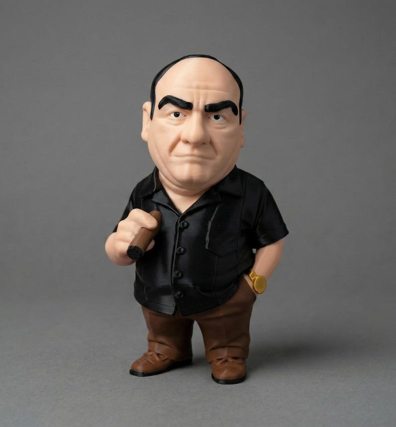 A Tony Soprano display statue wearing a black short-sleeve button-down shirt, brown pants, and a gold watch, holding a cigar.