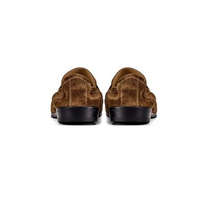 May include: A pair of brown suede loafers featuring a soft, textured upper material and a solid black heel. The shoes are shown from the back view, highlighting the rounded heel counter, the stitched seam detail, and the flat black outsole.