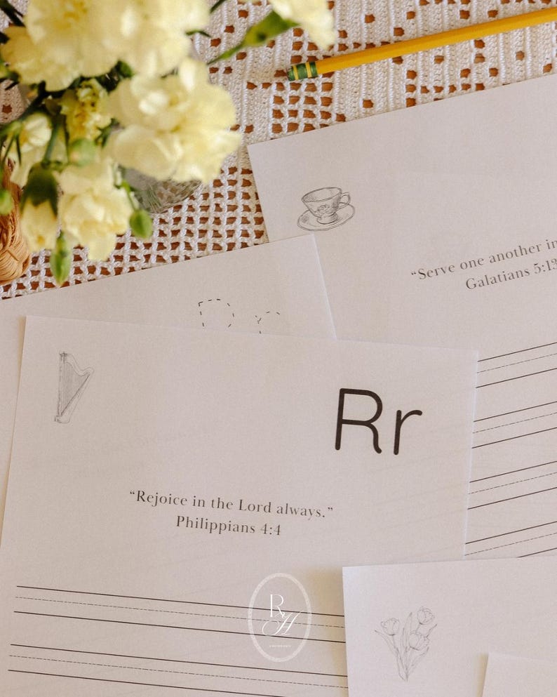 May include: A collection of white papers with handwritten text and illustrations, including a teacup, a harp, and a flower. The text includes the letter "Rr" and Bible verses. A bouquet of yellow flowers and a pencil are also visible.