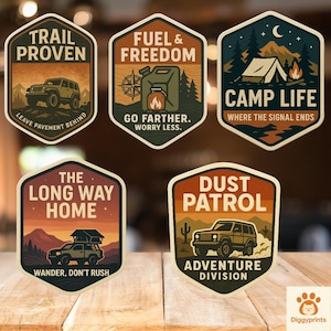 Può includere: Una collezione di cinque adesivi a tema avventura con vari design. Gli adesivi presentano illustrazioni di una jeep, scene di campeggio e paesaggi desertici, con testi come "Trail Proven" e "Camp Life". Gli adesivi sono su una superficie di legno.