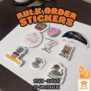 May include: A collection of assorted die-cut stickers featuring various graphic designs including a pineapple, a goose with a bat, a cat, a snake in a hat, and text-based logos. The stickers range from 2.5 cm to 8.9 cm in size.