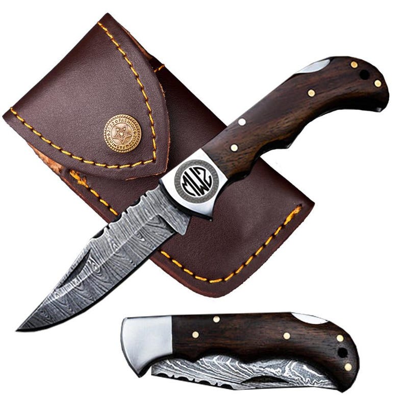 May include: A folding knife with a patterned blade and dark wood handle, accompanied by a brown leather sheath. The knife features a silver bolster with an engraved design. The sheath has a button closure and yellow stitching.