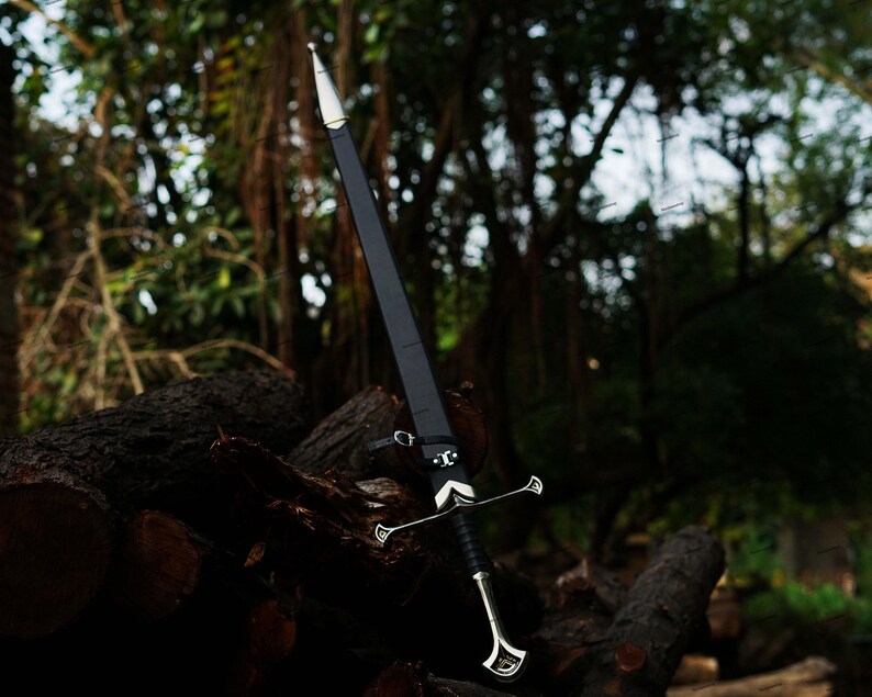 May include: A long, black sword with a silver crossguard and handle, resting against a backdrop of logs and foliage. The sword has a pointed tip and a leather sheath. The overall aesthetic suggests a medieval or fantasy theme.