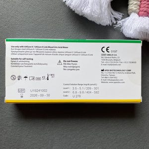 Pode incluir: Uma caixa branca e verde para um medidor de &aacute;cido &uacute;rico no sangue, com texto em v&aacute;rios idiomas. A caixa inclui informa&ccedil;&otilde;es sobre autoteste, uma gama de solu&ccedil;&atilde;o de controlo e um c&oacute;digo de produto. A data de validade &eacute; 2026-09-30.