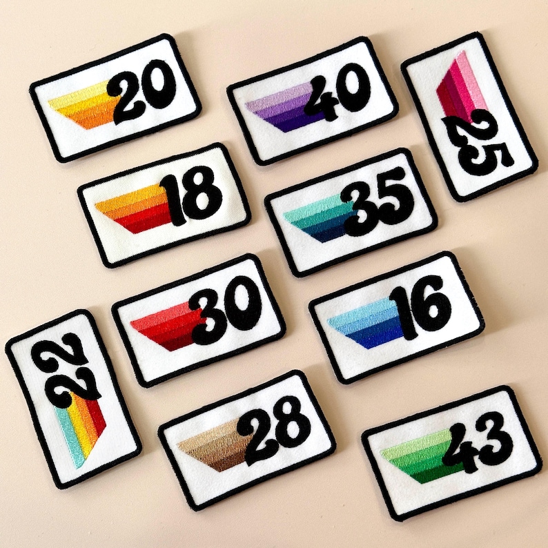 May include: Rectangular white patches with black borders, each displaying a number in bold black font and a colourful, embroidered gradient design. The patches feature numbers like 20, 40, 25, 18, 35, 16, 22, 30, 28, and 43.