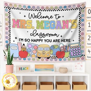 K&ouml;nnte beinhalten: Ein Klassenbanner mit dem Text "Welcome to MRS. MEGAN'S classroom. I'M SO HAPPY YOU ARE HERE." Das Banner hat einen rosa Rand mit Smileys und einem schwarz-wei&szlig; karierten Muster. Es zeigt Illustrationen zum Thema Schule.
