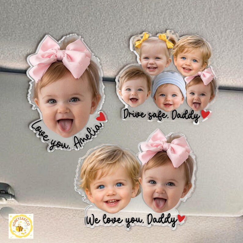 May include: Clear acrylic car charms featuring smiling baby faces with pink bows and the phrases "Love you, Amelia", "Drive safe, Daddy", and "We love you, Daddy". Each charm has a red heart accent.