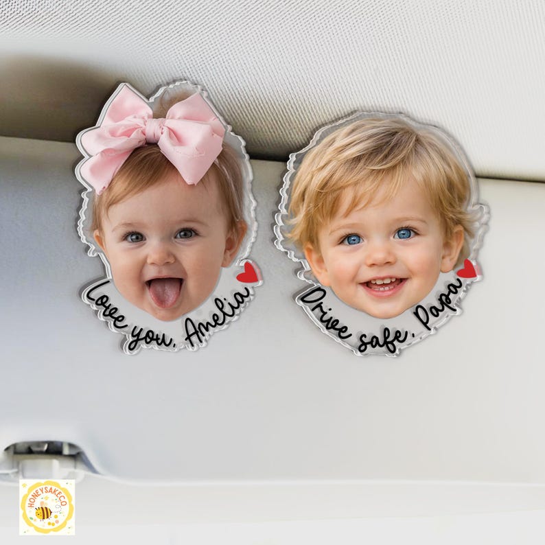 May include: Two clear acrylic car charms with photos of children. One has a pink bow and the text "Love you, Amelia" with a red heart. The other says "Drive safe, Papa" with a red heart.