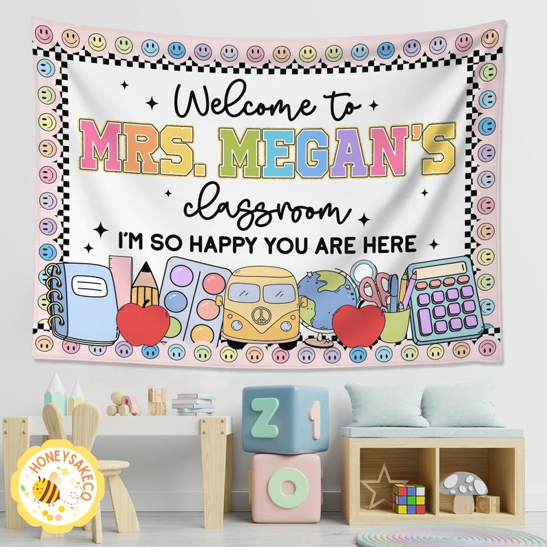 K&ouml;nnte beinhalten: Ein Wandteppich f&uuml;r das Klassenzimmer mit dem Text "Welcome to MRS. MEGAN'S classroom. I'M SO HAPPY YOU ARE HERE." Das Design umfasst Illustrationen zum Thema Schule wie einen Apfel, einen Globus und einen Bus, umrahmt von einem Rand aus Smileys und Schachbrettmustern.