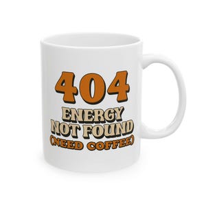 Peut inclure: Mug en céramique blanche avec l'inscription "404 ENERGY NOT FOUND (NEED COFFEE)" en marron et beige dans une police rétro. La tasse a une anse incurvée et est conçue pour les boissons chaudes.