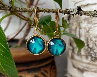 May include: A pair of gold dangle earrings with round blue and green resin cabochons. The cabochons have a swirling pattern.