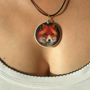 Op de afbeelding: Een zilveren ketting met een ronde hanger met een realistische afbeelding van een rode vos.