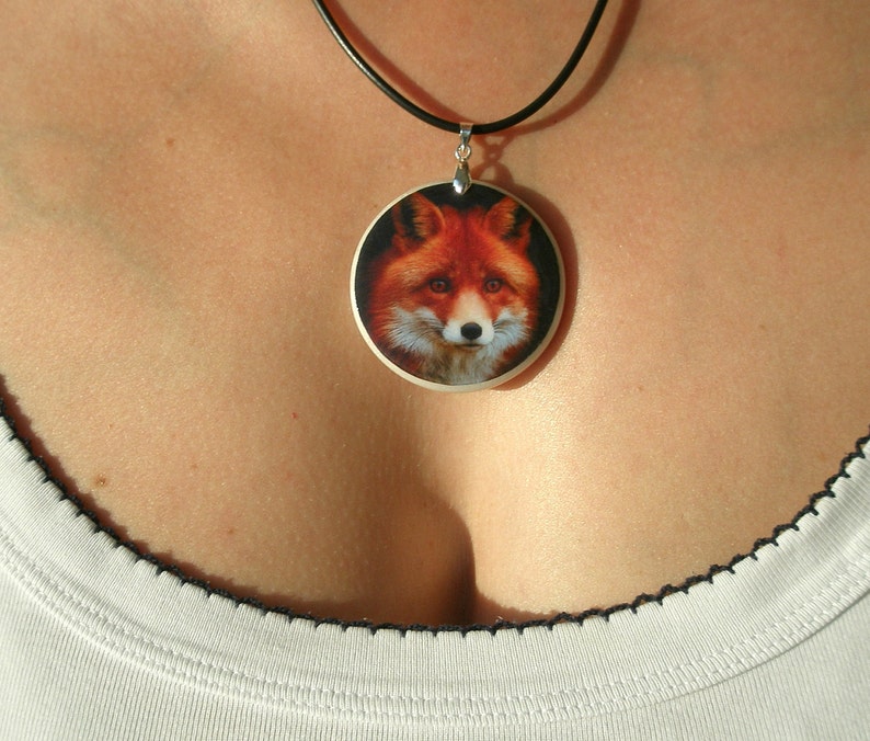 Op de afbeelding: Een zilveren ketting met een ronde hanger met een realistische afbeelding van een rode vos.