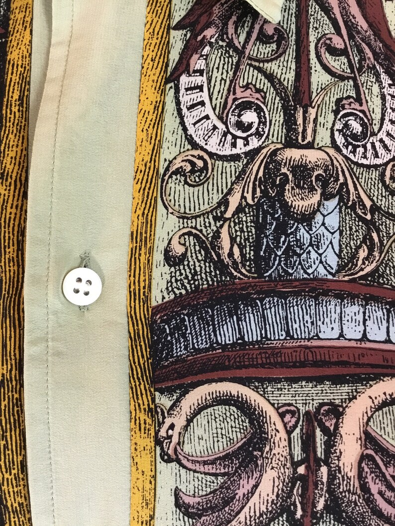 May include: A beige button-up shirt with a yellow and brown patterned design. The pattern features a stylized floral design with intricate details.