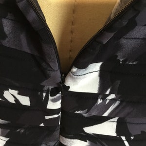 May include: Black and white abstract print dress with a zip closure at the front.