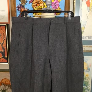 May include: A pair of gray pleated pants with a subtle pinstripe pattern. The pants have a button closure and two front pockets.