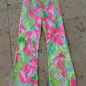 May include: A pair of wide-leg pants with a floral print featuring pink, green, and blue colors. The pants have a wide leg opening and a high waist.