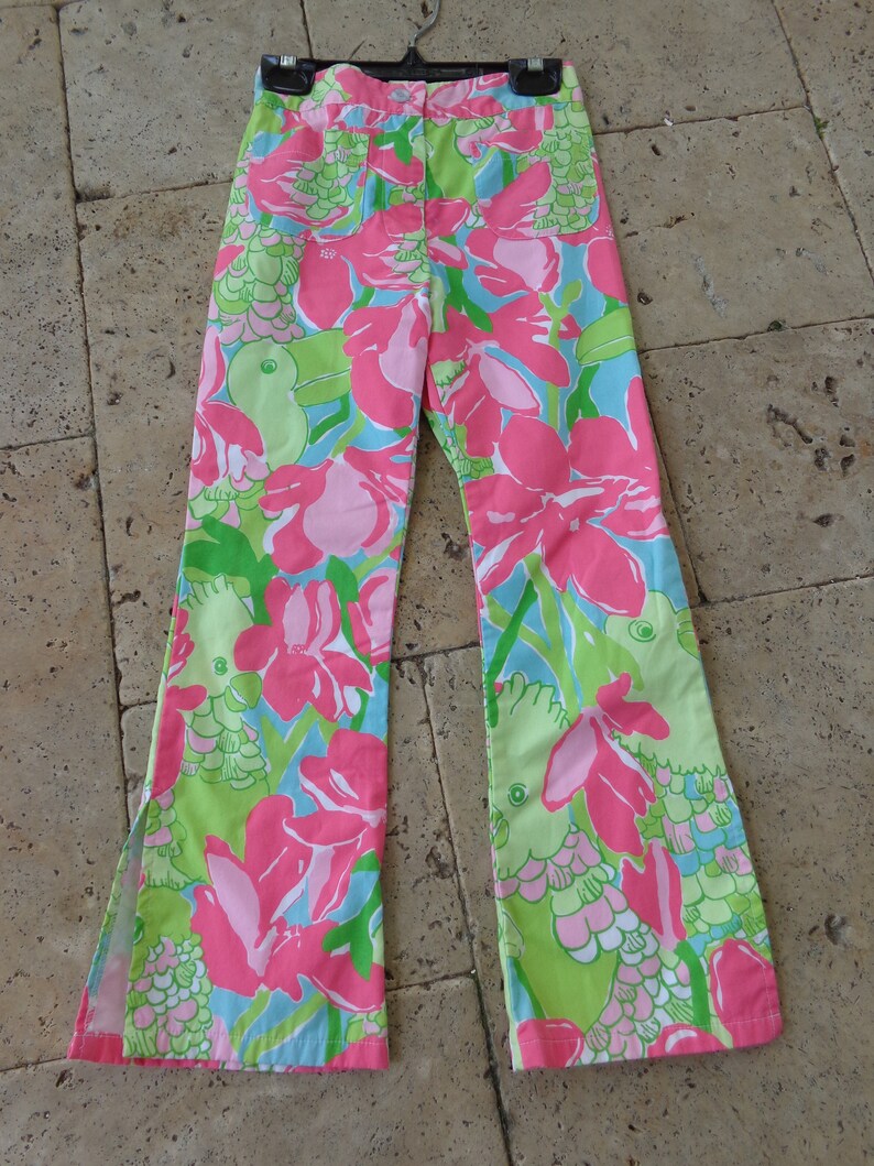 May include: A pair of wide-leg pants with a floral print featuring pink, green, and blue colors. The pants have a wide leg opening and a high waist.