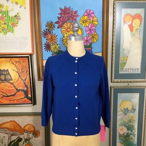 May include: A royal blue cardigan sweater with a round neckline and button closure. The cardigan has long sleeves and is made of a soft, knit fabric.