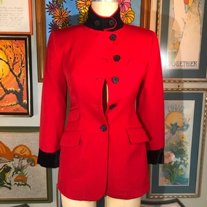 May include: A red blazer with a black collar and cuffs. The blazer has a single button closure and two pockets.