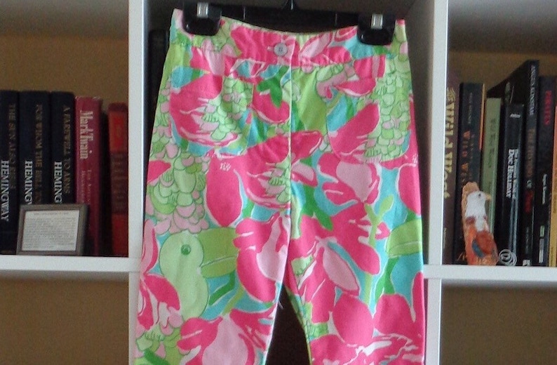 May include: Pink, green, and blue patterned pants with a floral design. The pants have a button and zipper closure.