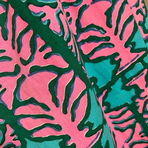 K&ouml;nnte beinhalten: Nahaufnahme eines rosa Stoffes mit einem abstrakten Muster in Gr&uuml;n und Blau. Das Muster &auml;hnelt Korallen oder Seegras.