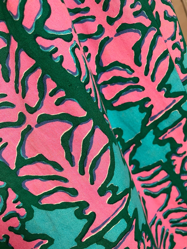 K&ouml;nnte beinhalten: Nahaufnahme eines rosa Stoffes mit einem abstrakten Muster in Gr&uuml;n und Blau. Das Muster &auml;hnelt Korallen oder Seegras.