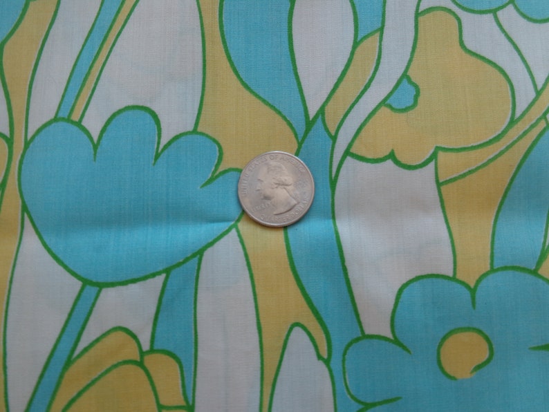 May include: A fabric with a repeating pattern of stylized flowers in shades of blue, green, and yellow. The fabric is white with a subtle sheen.