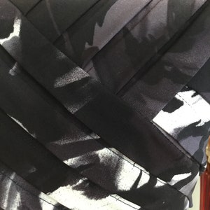 May include: Black and white abstract print fabric with black ribbon accents. The fabric has a soft, flowing texture.