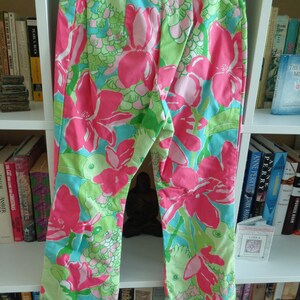 May include: Pink and green floral print pants with a wide leg and a high waist.