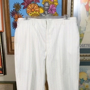 May include: White pinstripe pants with a black pinstripe pattern. The pants have a zipper fly and belt loops.