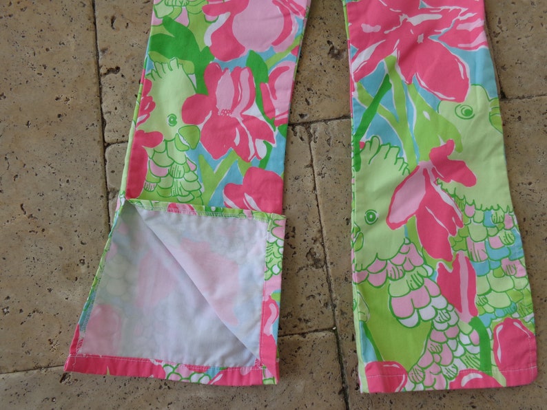 May include: A pair of pink and green pants with a floral print featuring parrots. The pants have a white lining and are made of a soft, lightweight fabric.