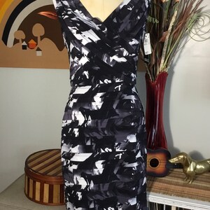 May include: A black and white sleeveless dress with a geometric print. The dress has a v-neckline and a fitted silhouette.