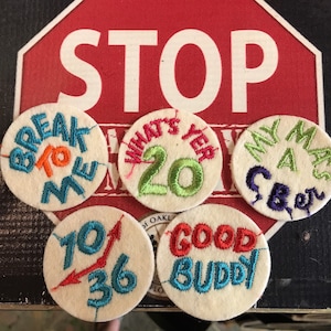 Könnte beinhalten: Fünf gestickte Aufnäher mit verschiedenen Sprüchen. Die Aufnäher sind weiß mit bunter Stickerei. Die Sprüche lauten "Break to Me", "What's Yer 20", "My Ma's a CBer", "70/36" und "Good Buddy".