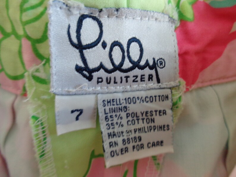 May include: A white tag with the Lilly Pulitzer logo and size 7. The tag lists the fabric content as 100% cotton for the shell and 65% polyester and 35% cotton for the lining. The tag also states "Made in Philippines" and provides a care instruction.