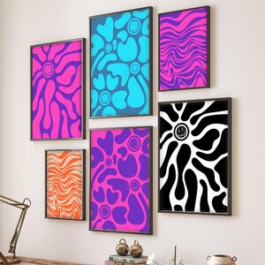 Puede incluir: Una colección de impresiones artísticas enmarcadas con diseños psicodélicos vibrantes. Las impresiones presentan colores llamativos como rosa, azul, naranja y negro, con caras sonrientes y patrones abstractos. Los marcos son negros.
