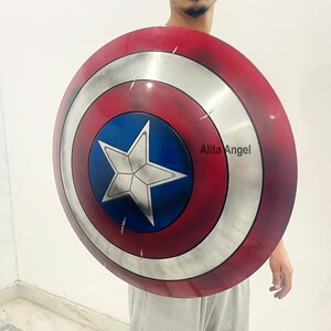 May include: A Captain America shield, featuring a red and white concentric circle design with a blue central area. A white star is centered on the blue area. The shield is round and appears to be made of metal.