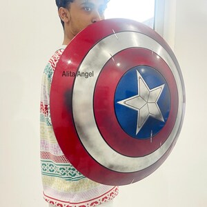 May include: A Captain America shield with a red, white, and blue color scheme. The shield features a white star on a blue circle, surrounded by white and red concentric rings. The shield is a prop or collectible.