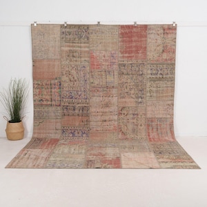Pode incluir: Um grande tapete retangular de patchwork com uma aparência desgastada e vintage. O tapete apresenta uma variedade de retalhos retangulares em tons de vermelho, rosa, bege e roxo. Os retalhos têm padrões florais e geométricos intrincados.