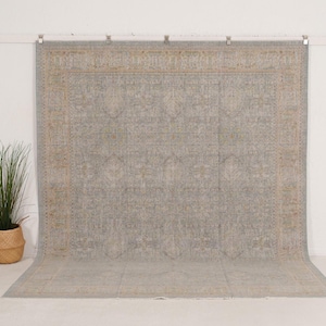 May include: A large rectangular area rug featuring a muted light blue and beige color palette. The rug displays a detailed, symmetrical pattern with intricate floral and geometric motifs throughout the center and a wide, ornate decorative border.