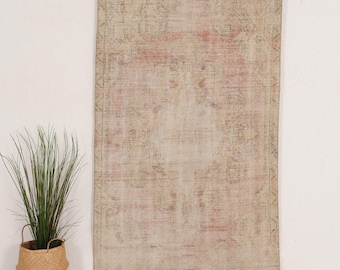 Può includere: Un tappeto rettangolare caratterizzato da una palette sbiadita e tenue di rosa antico, beige e crema. Il tappeto presenta un medaglione centrale circondato da intricati motivi geometrici e floreali simmetrici su tutta la superficie.