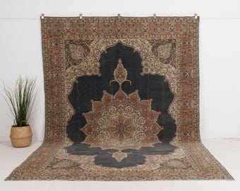 Puede incluir: Una alfombra rectangular grande con un diseño de medallón floral ornamentado. La alfombra presenta un centro azul oscuro con un patrón floral multicolor detallado en tonos de marrón, beige y rojo. El borde es un patrón complementario en tonos similares.