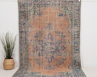 May include: A rectangular area rug featuring a large central medallion in shades of blue and green set against a muted peach background. The rug has a wide decorative border with intricate floral patterns in blue, green, and cream tones.