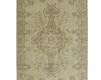Può includere: Un tappeto rettangolare in una palette di colori beige e marrone chiaro. Il tappeto presenta un design a medaglione centrale con motivi floreali e vegetali simmetrici, circondato da un bordo dettagliato con elementi botanici ripetuti.
