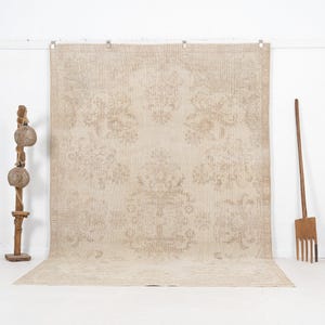 May include: A large, rectangular area rug featuring a monochromatic beige and light tan color palette. The rug displays an intricate, symmetrical damask-style floral pattern woven throughout the surface, complete with a detailed decorative border.