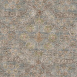 May include: A woven textile featuring a repeating pattern of soft blue, muted brown, and pale green circular motifs. The fabric displays a dense, textured grid structure with a subtle, weathered appearance created by the interplay of these colors.
