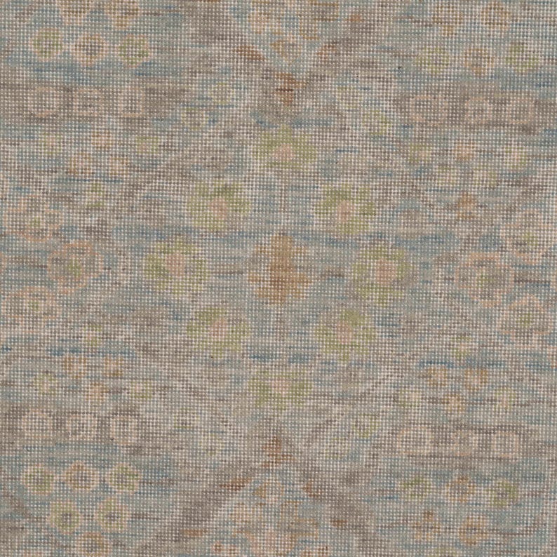 May include: A woven textile featuring a repeating pattern of soft blue, muted brown, and pale green circular motifs. The fabric displays a dense, textured grid structure with a subtle, weathered appearance created by the interplay of these colors.