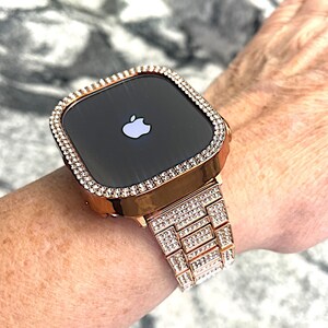 Puede incluir: Un Apple Watch de oro rosa con una banda y un bisel engastados con diamantes. La esfera del reloj es negra y presenta el logotipo de Apple.