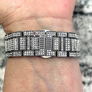 Op de afbeelding: Een zilveren horlogeband met een rij kleine, heldere stenen.