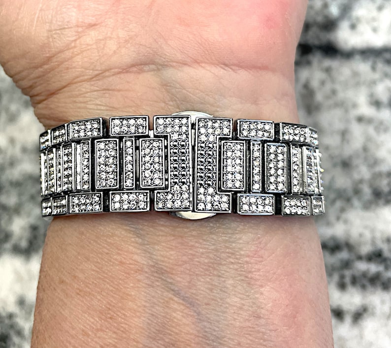 Op de afbeelding: Een zilveren horlogeband met een rij kleine, heldere stenen.